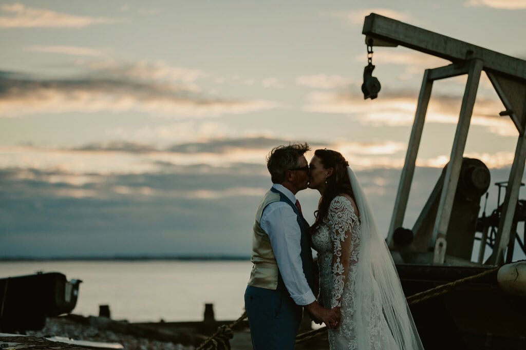 Couple kissing at sunset on their wedding day.