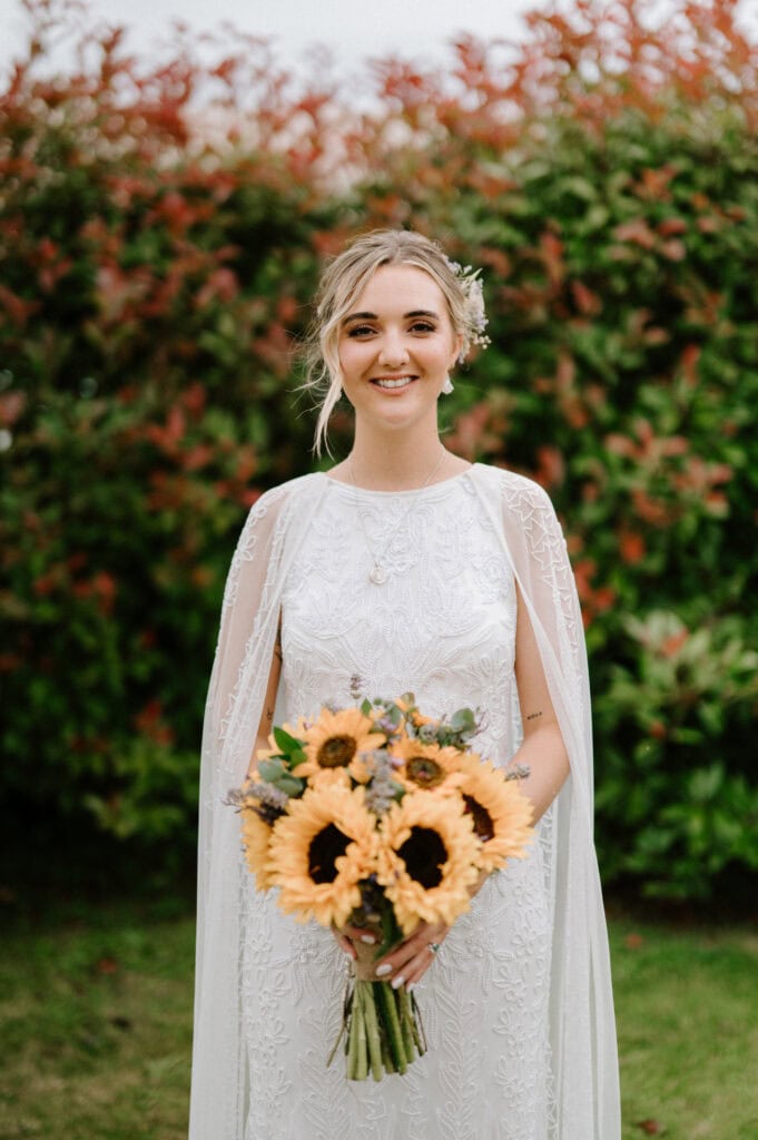 Bride holding sunflower bouquet in garden wedding.