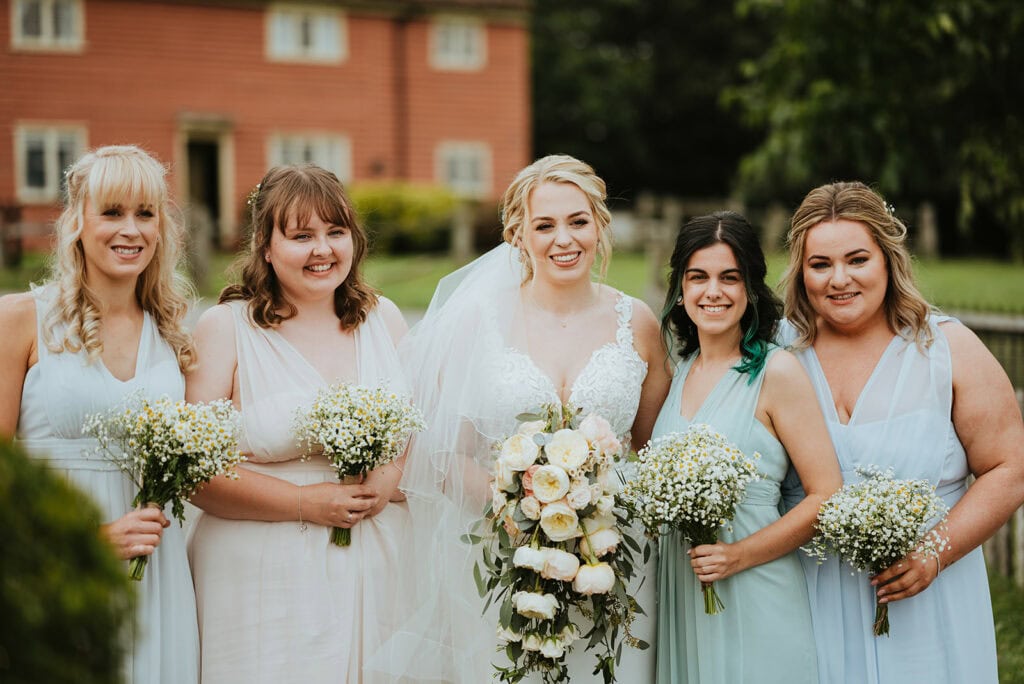 Bride and bridesmaids holding bouquets outdoors.