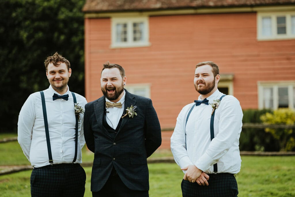 Groom with groomsmen in front of a rustic house.