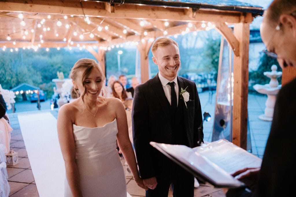 Newlyweds at wedding ceremony under fairy lights.
