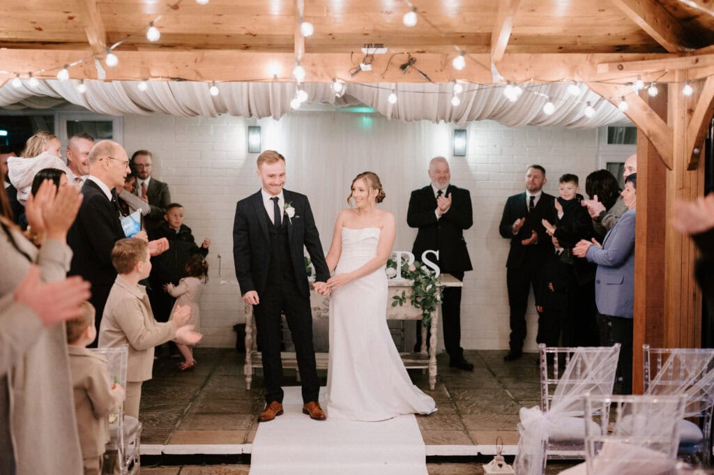 Bride and groom celebrated by guests at indoor wedding.