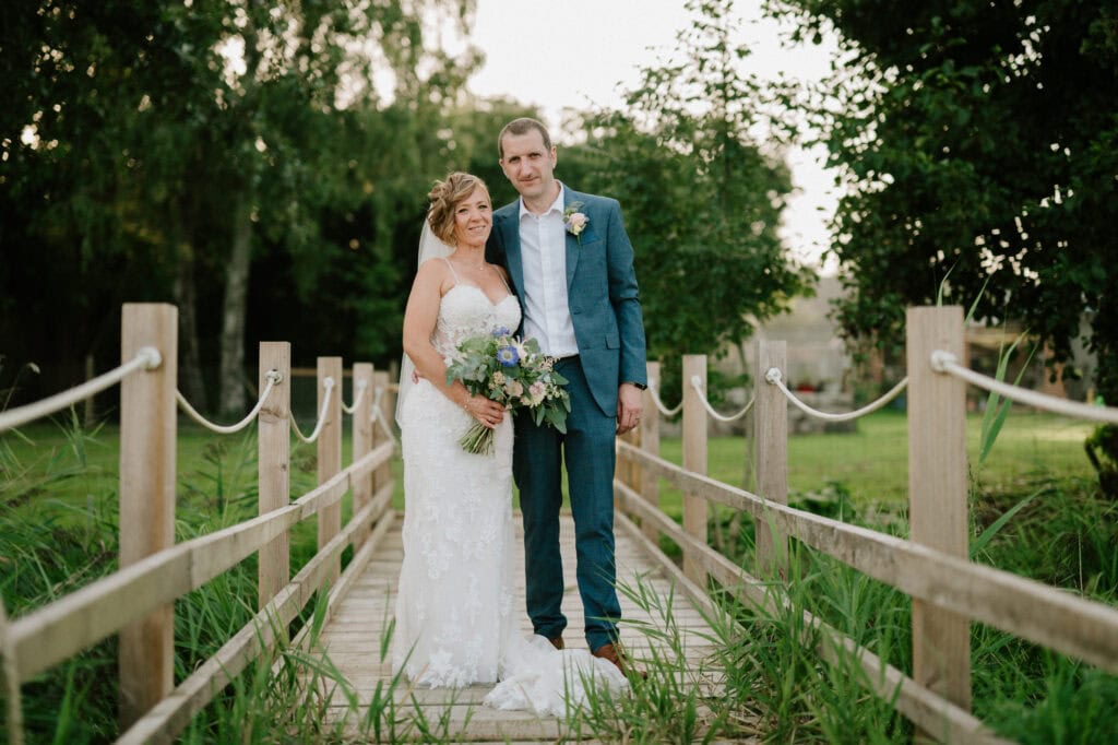 Bride and groom on wooden bridge.