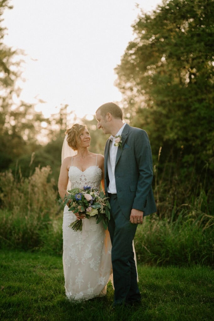 Bride and groom smiling in a garden sunset.