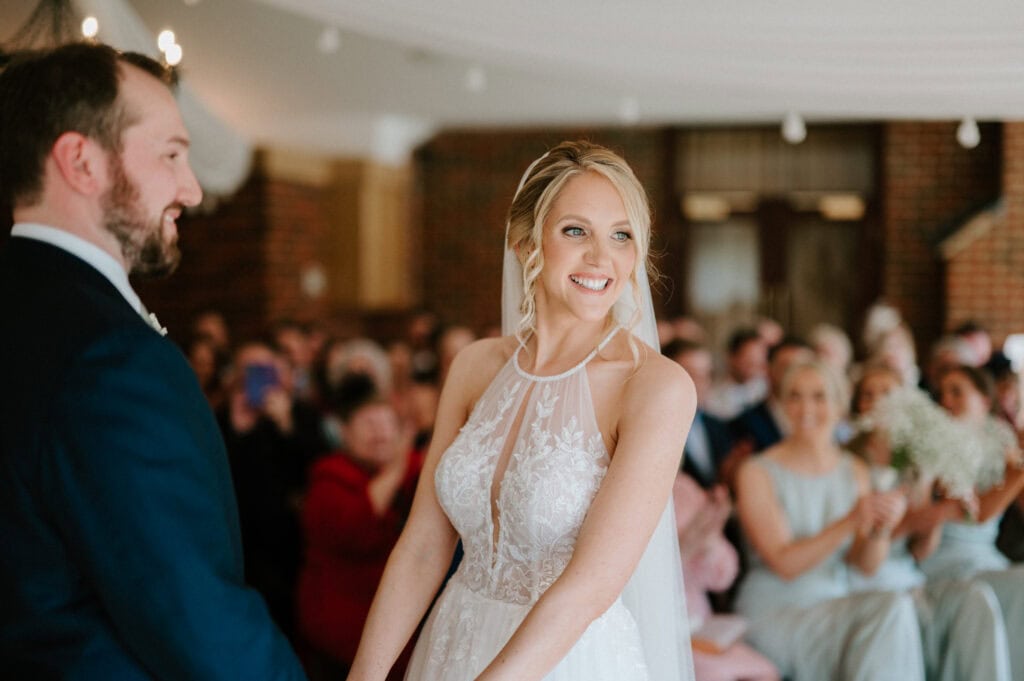 Bride and groom during wedding ceremony, smiling guests.