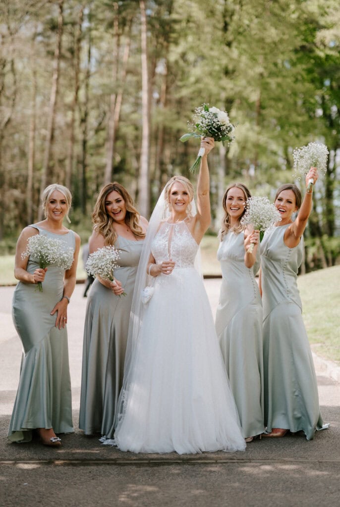 Bride and bridesmaids celebrating outdoors with flowers.