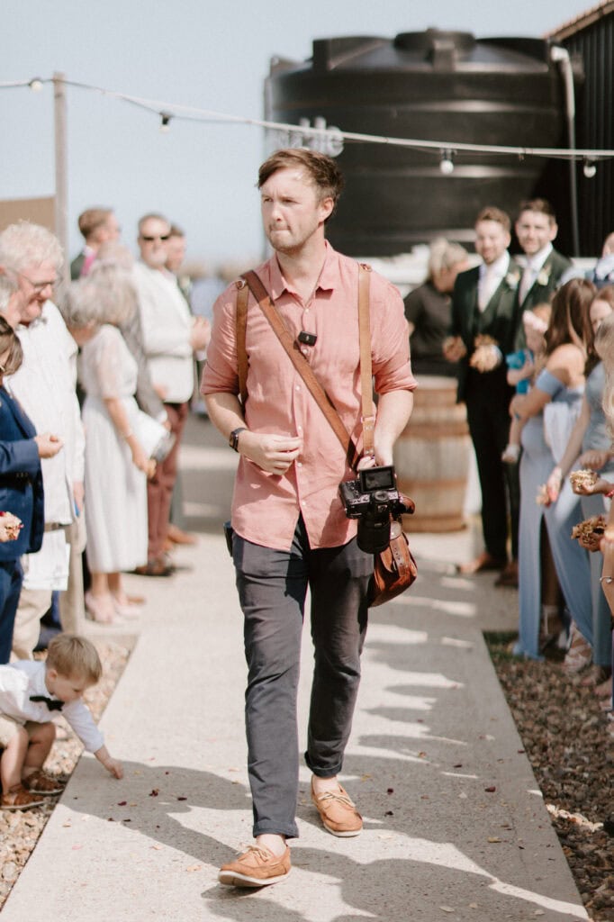 Photographer walking during an outdoor wedding ceremony.