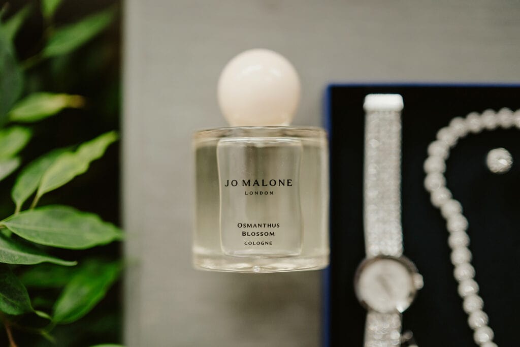 A bottle of Jo Malone London Osmanthus Blossom cologne is displayed next to a watch and jewelry.