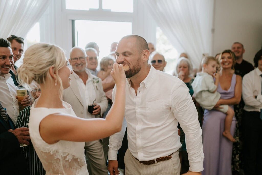 Bride feeds groom cake at wedding reception.