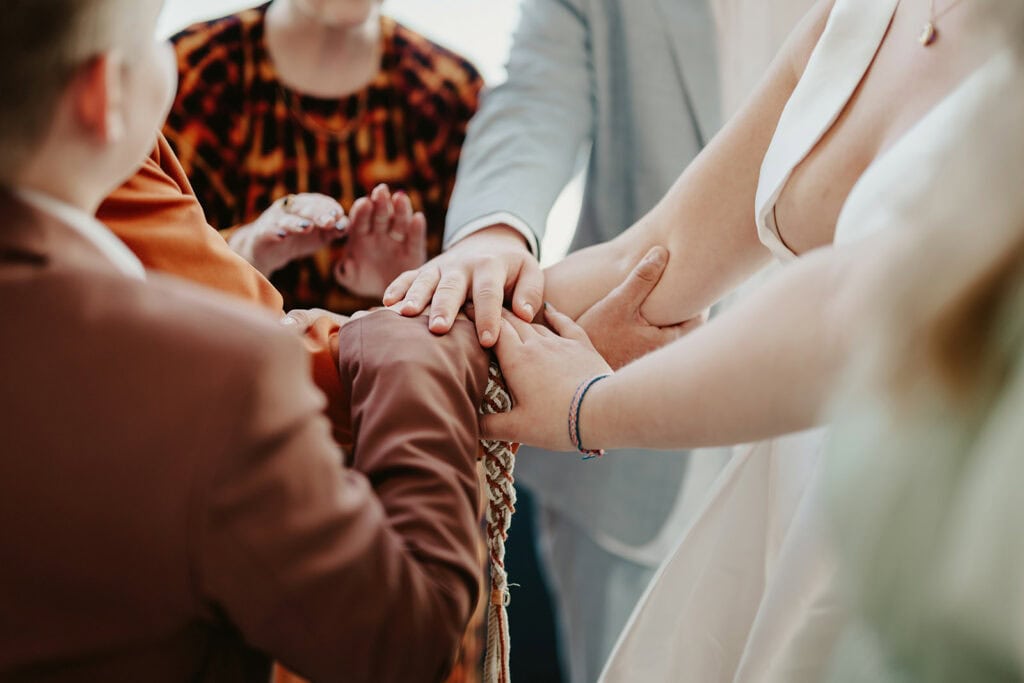 A group of people, dressed formally, holding hands together in a circle, possibly participating in a ceremonial or celebratory activity.