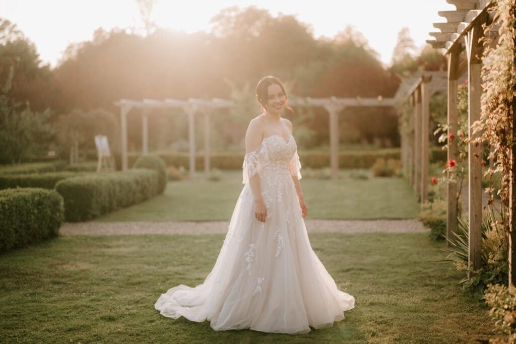 Bride in wedding dress in garden at sunset