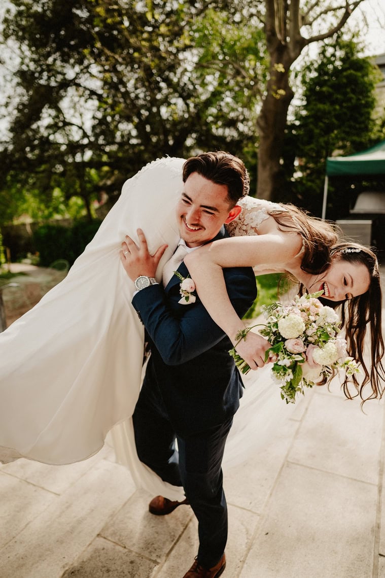 Gravy picks up his bride and carries her over his shoulder both of them are laughing