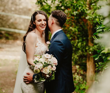 The groom telling the bride a secret which makes her laugh