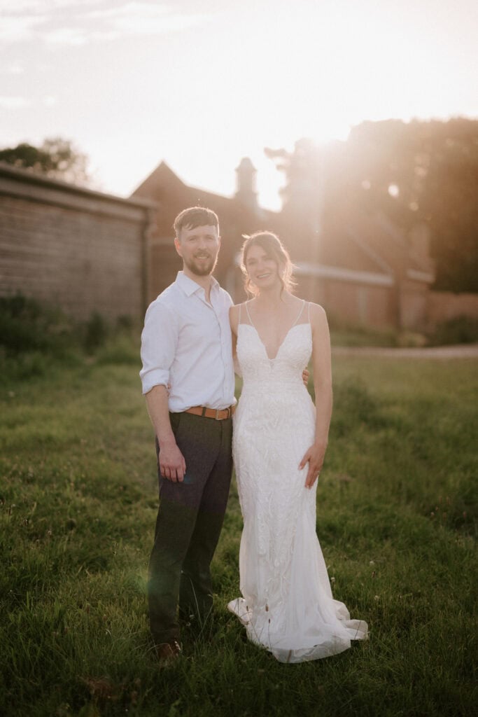 Wedding couple smiling in a sunny field.