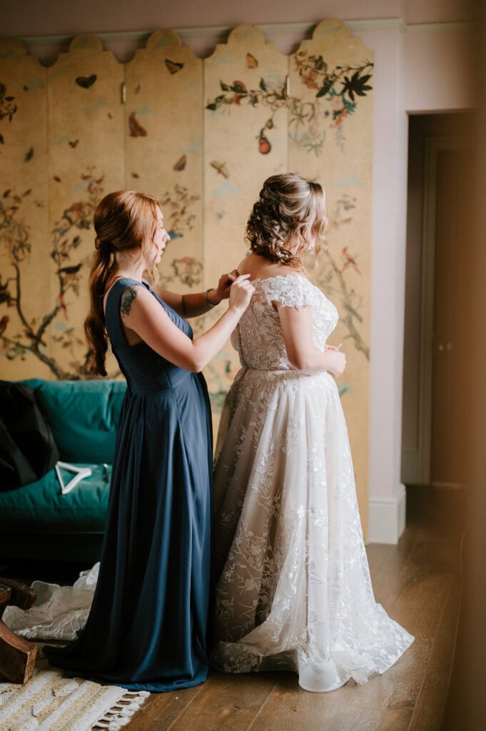 Bridesmaid helping bride with dress