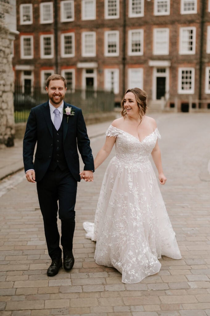 Smiling couple holding hands in wedding attire.