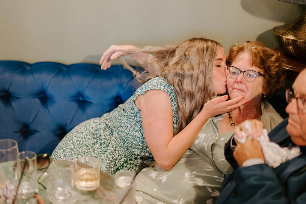 Woman kisses elderly woman on the cheek.