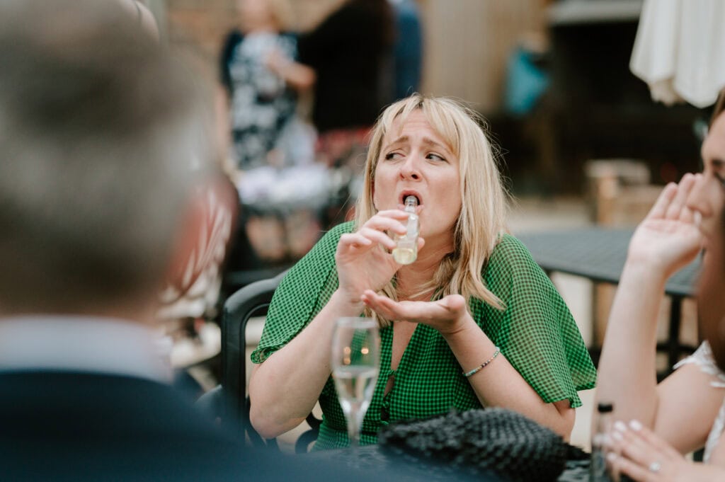 Woman drinking from a small bottle.