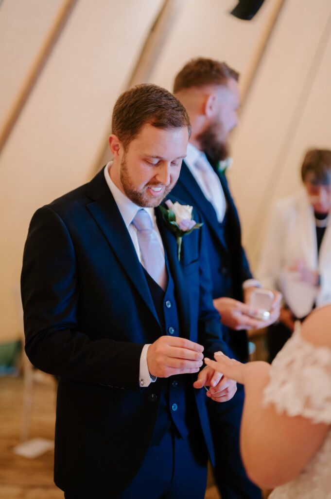 Groom placing ring on bride's finger