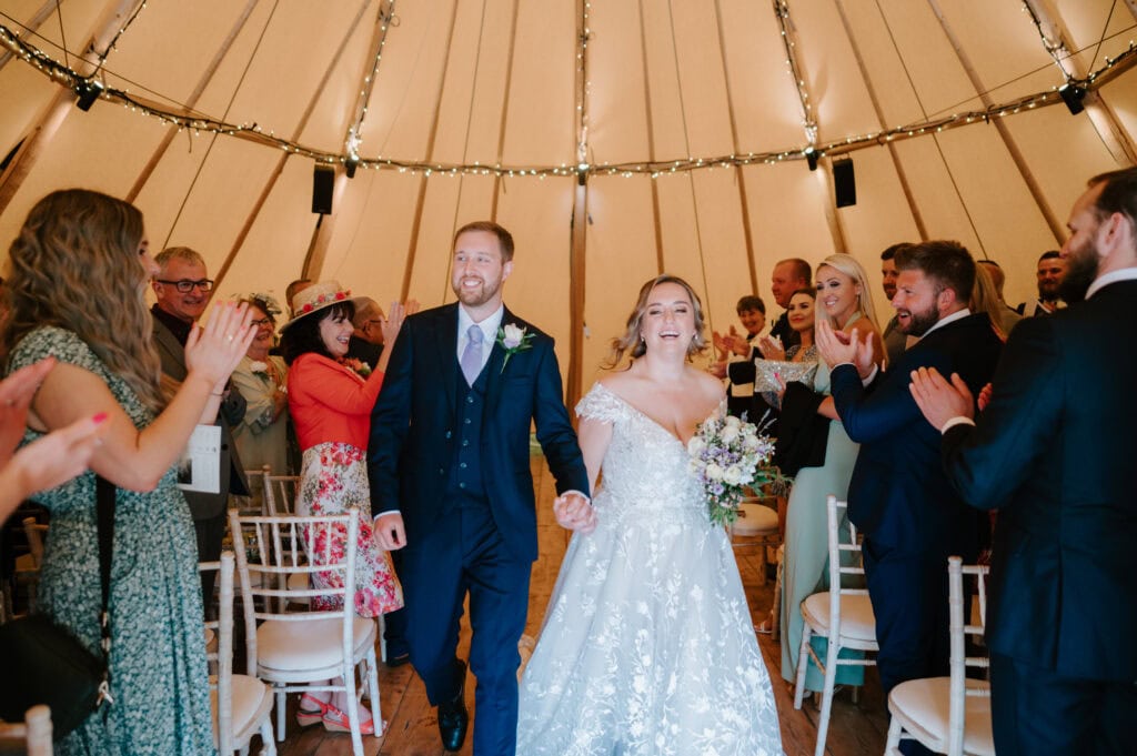 Bride and groom walk down aisle smiling