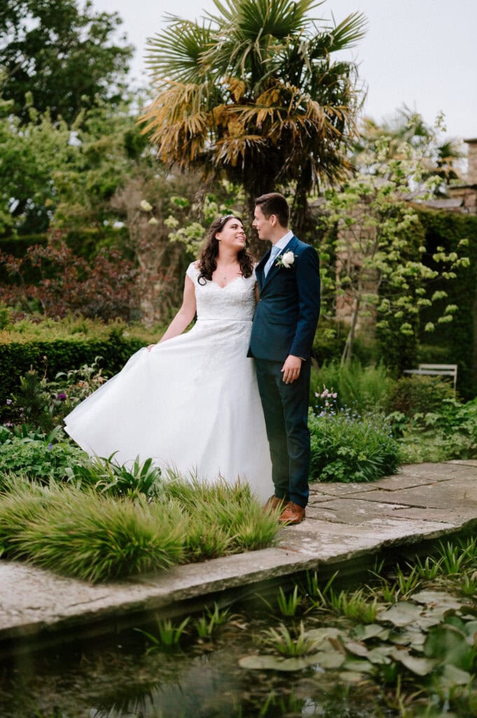 A man and woman in a wedding dress stand joyfully at the Chapel House Estate.