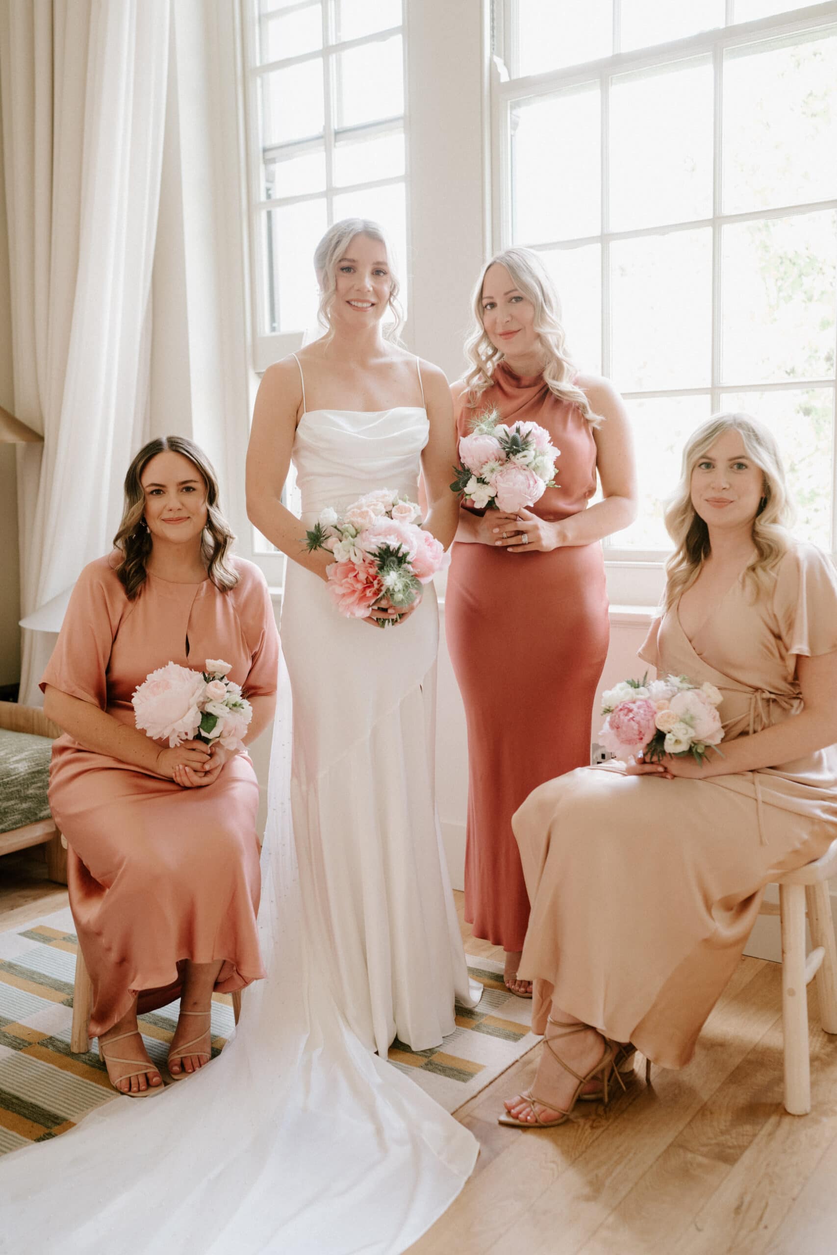 Bride with bridesmaids holding bouquets indoors.