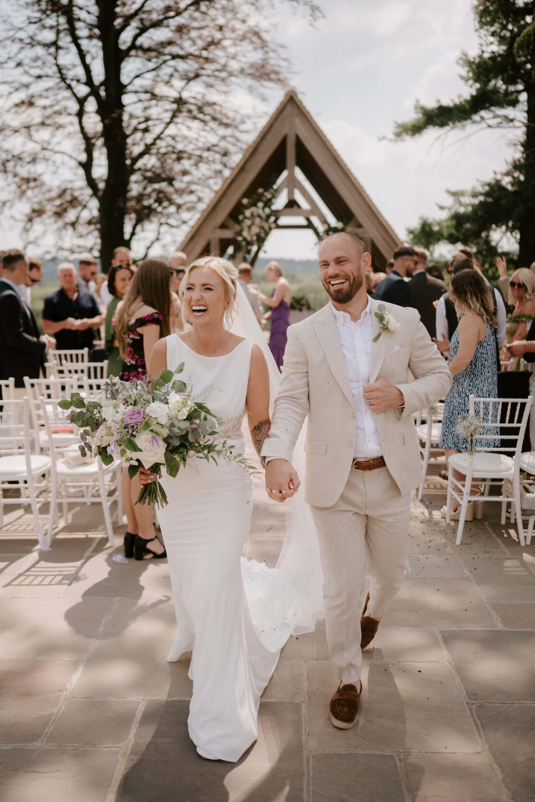 Happy couple walking down the aisle at outdoor wedding.
