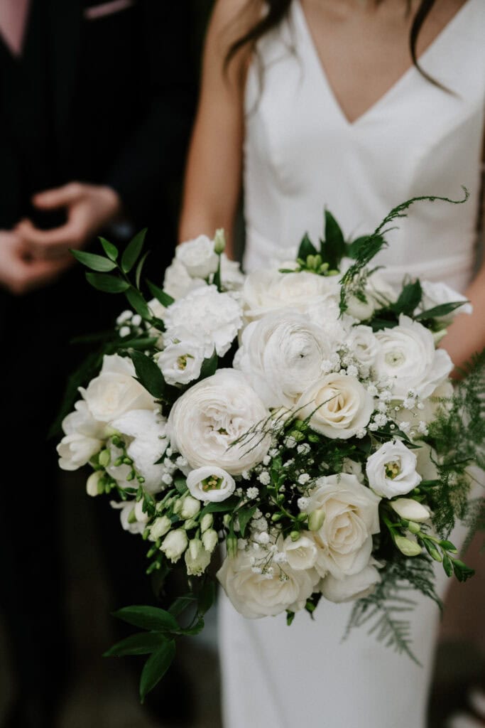 Bride holding white floral wedding bouquet.
