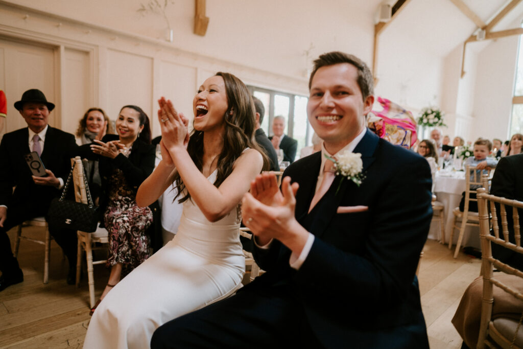 Bride and groom clapping at wedding ceremony reception.