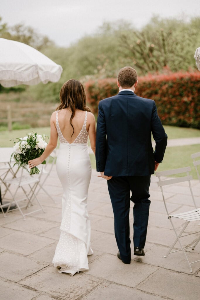 Bride and groom walking in garden.