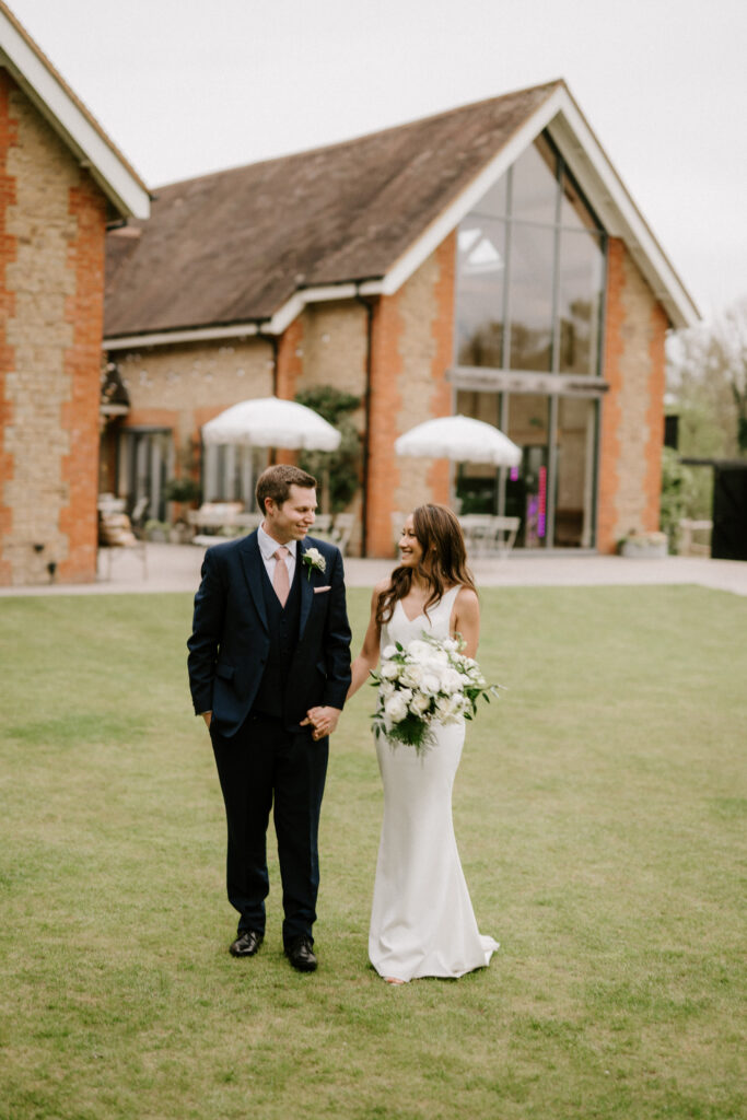 Bride and groom holding hands outside wedding venue.