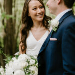Bride and groom smiling in forest setting.