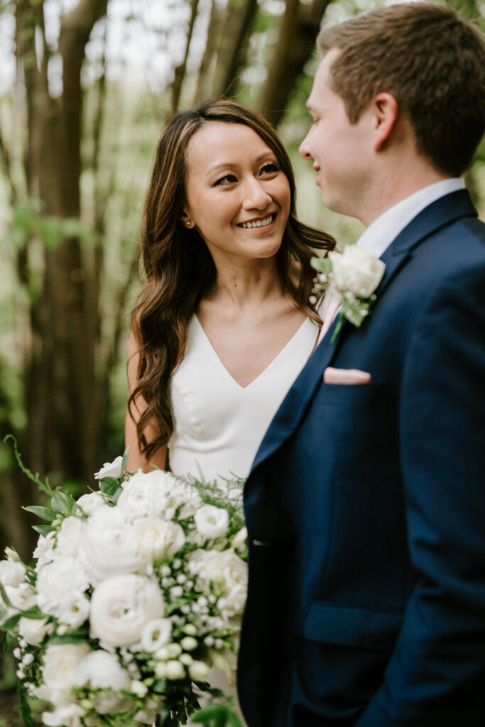 Bride and groom smiling in forest setting.