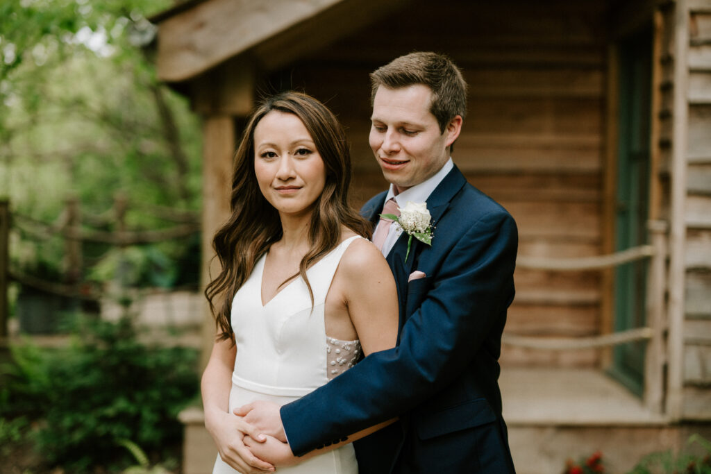 Bride and groom embracing in a garden.