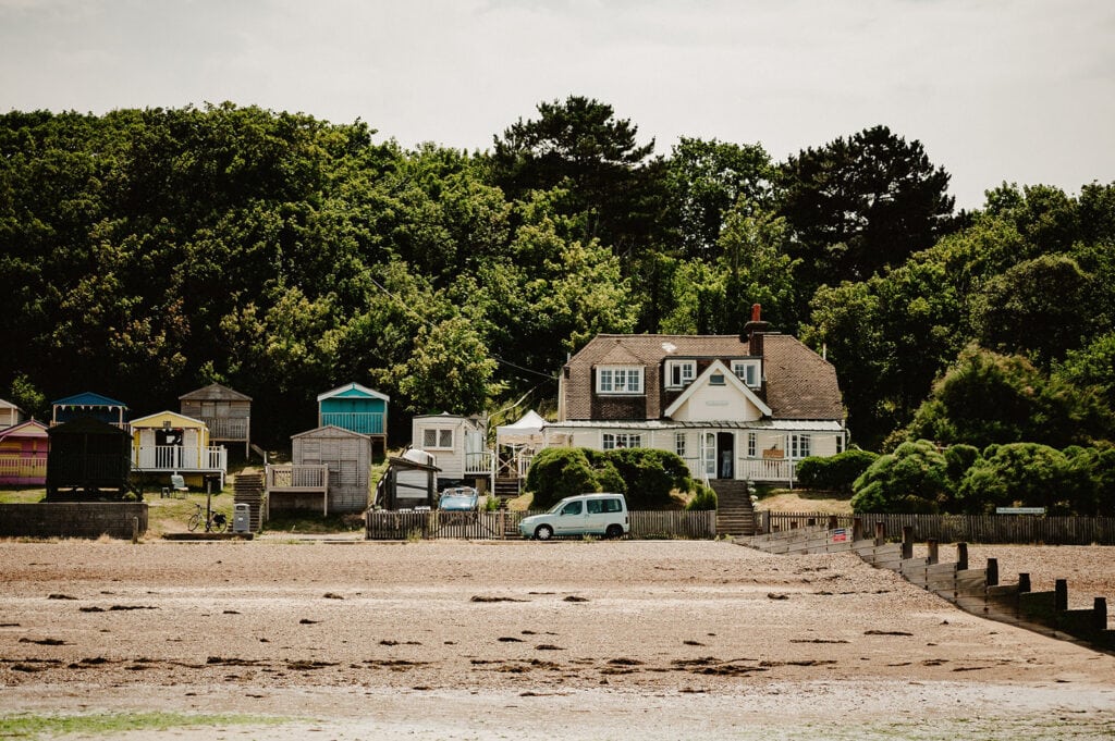 Beachfront house with colourful huts and trees.