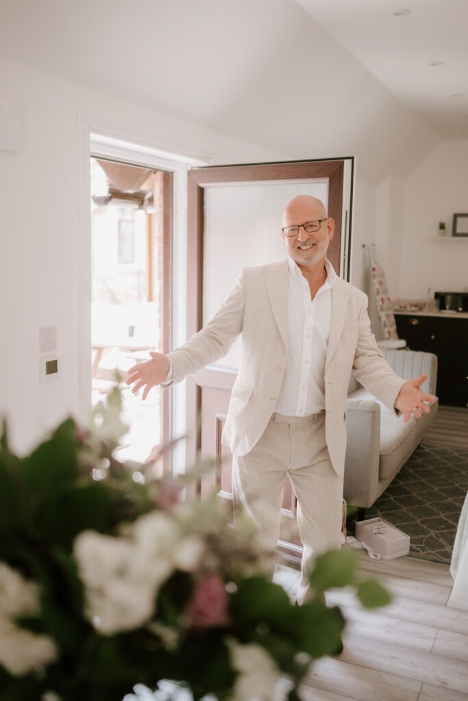 Man smiling and opening arms in living room doorway.