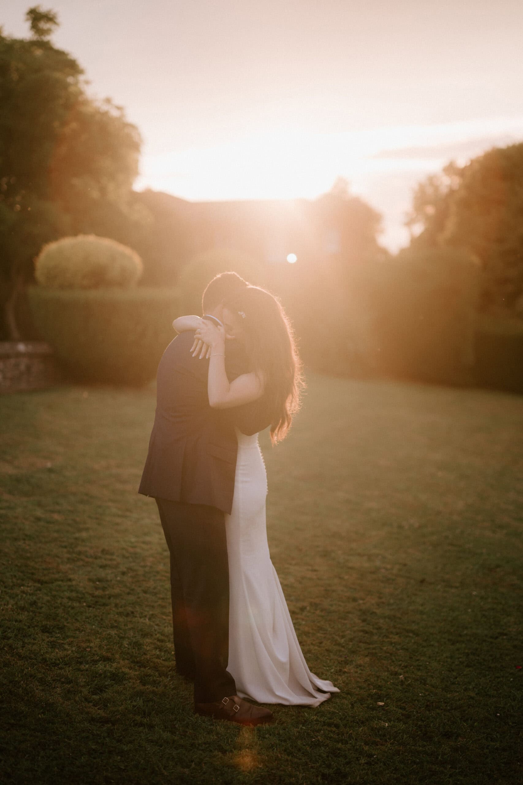 Couple embracing at sunset in a garden.
