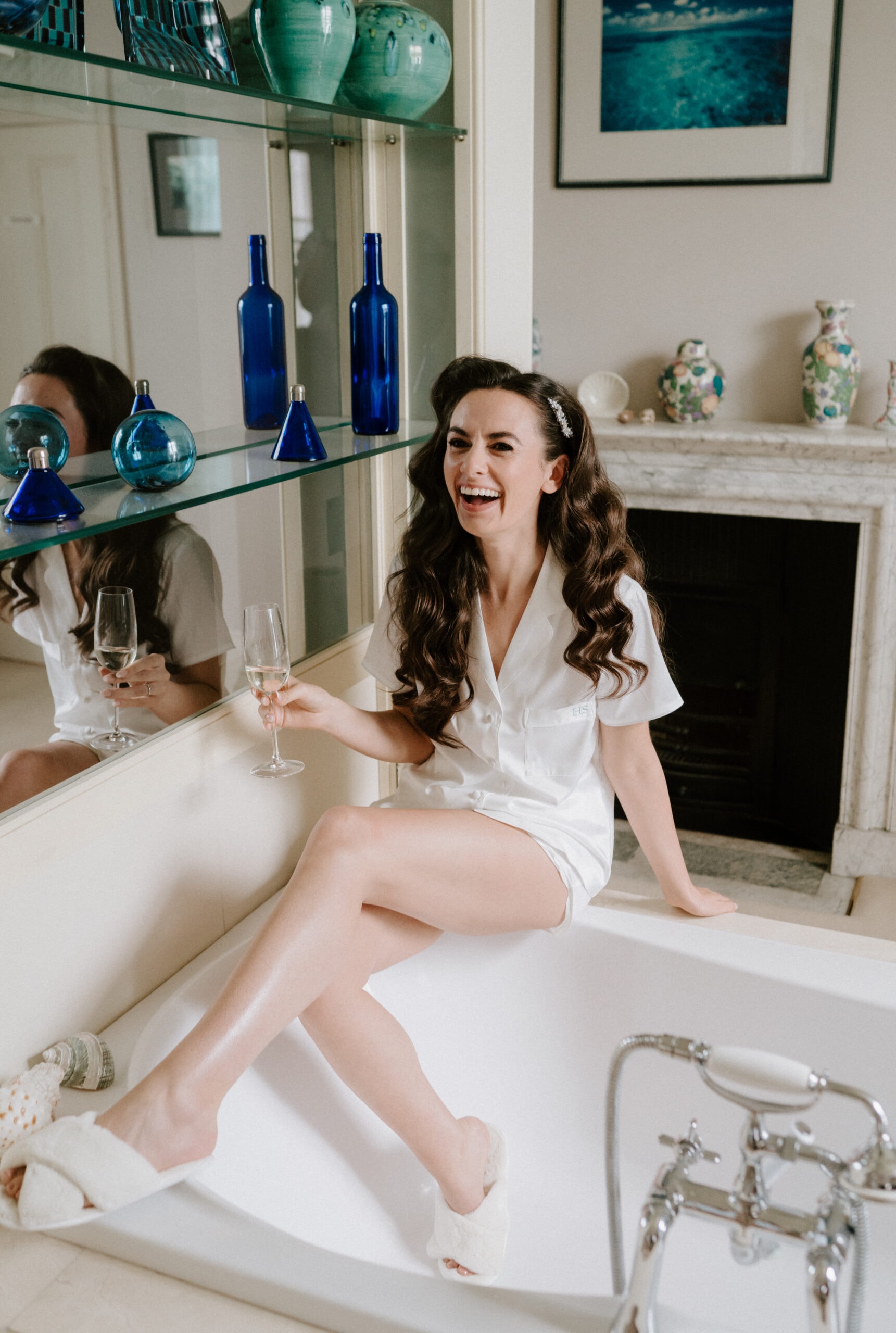 Woman in pyjamas laughing with a glass of wine.