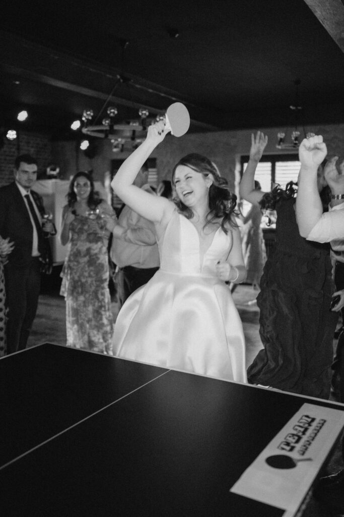 Bride playing ping pong at wedding reception.