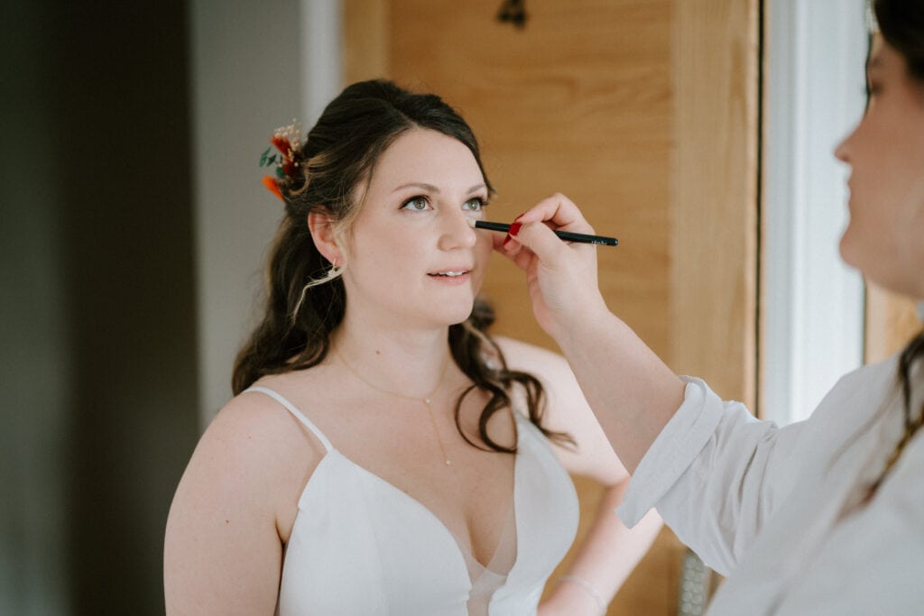 Bride getting her makeup done before wedding ceremony.