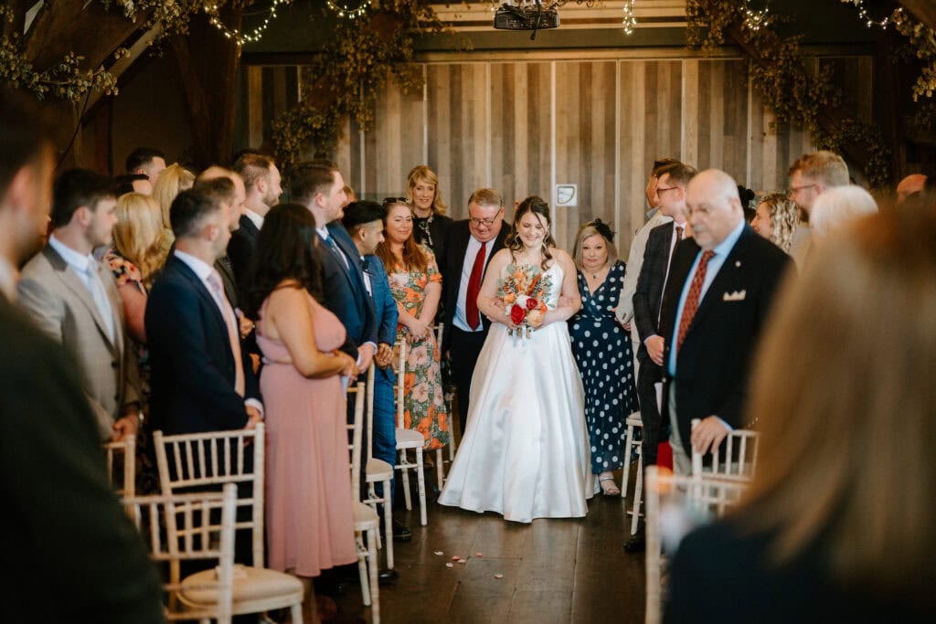 Bride walking down the aisle with guests watching