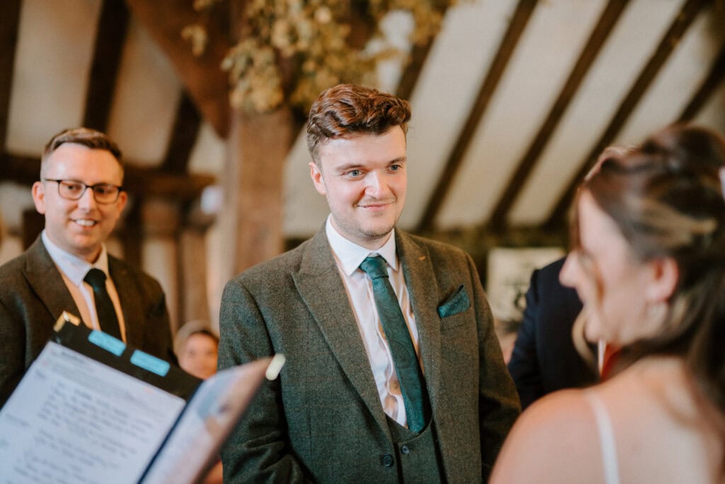 Two men smiling at wedding ceremony.
