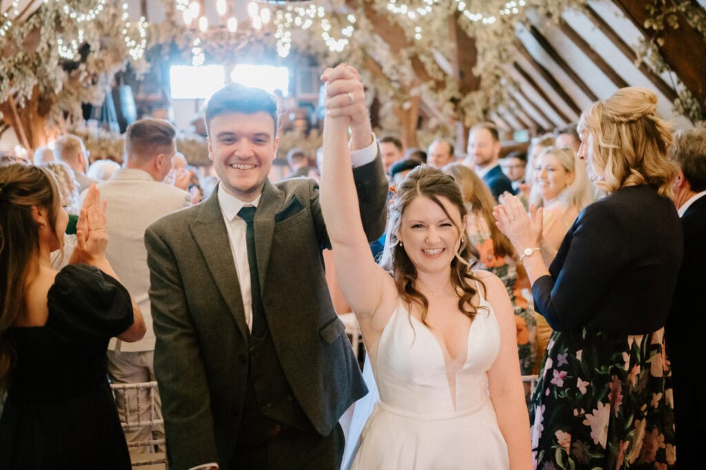 Happy couple celebrates wedding day with raised hands.