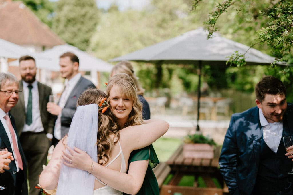Bride hugging guest at outdoor wedding reception.