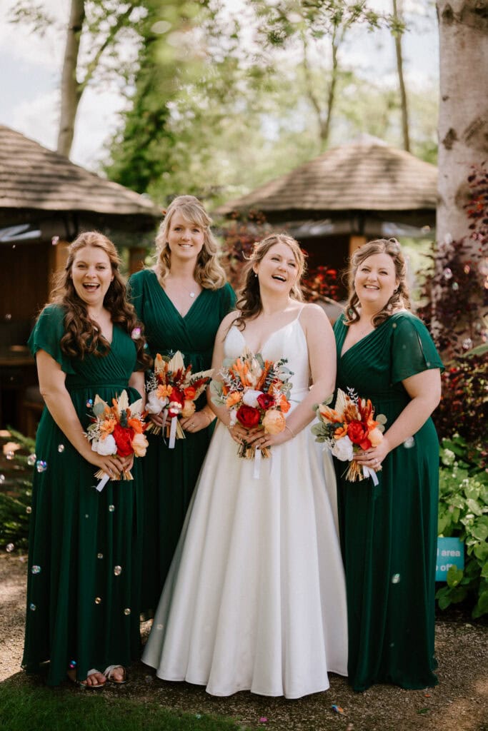 Bride and bridesmaids smiling, holding bouquets.