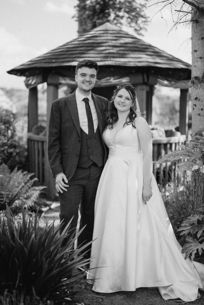 Bride and groom pose outside gazebo on wedding day.