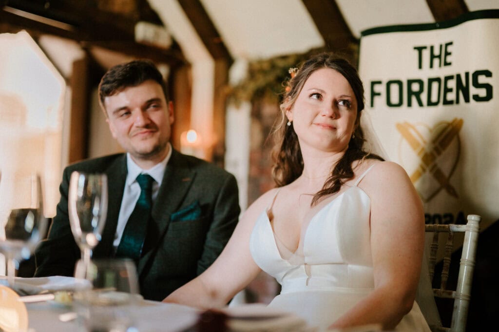 Bride and groom listen during wedding reception.