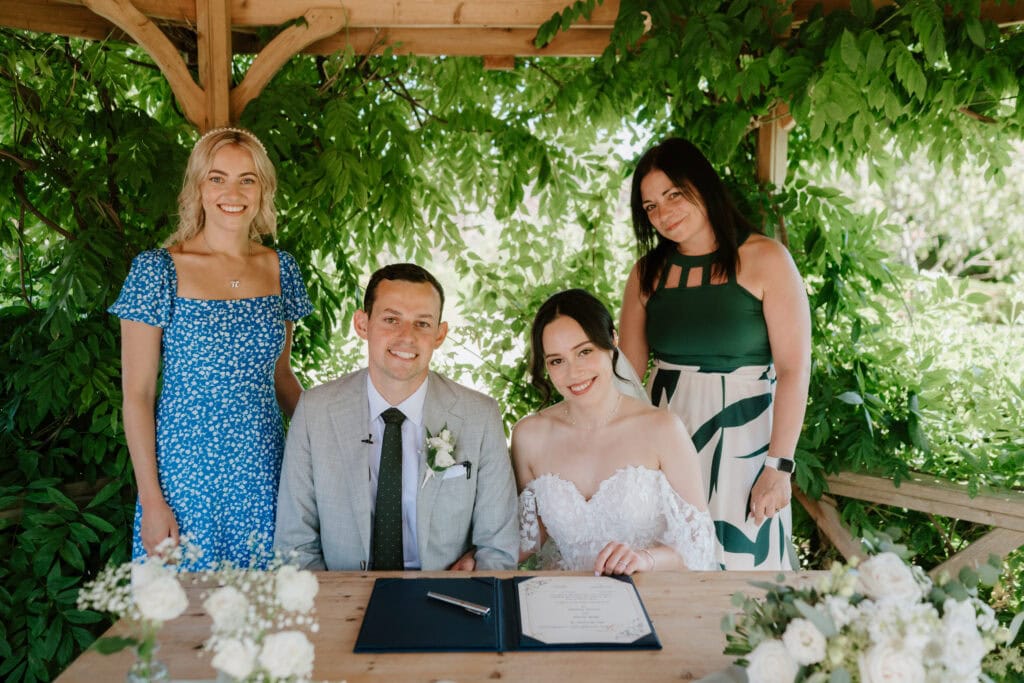 Wedding couple signing register with friends.