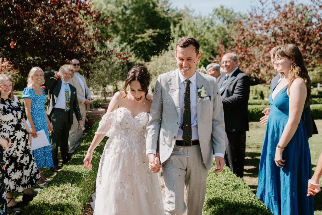 Bride and groom celebrate wedding with guests outdoors.