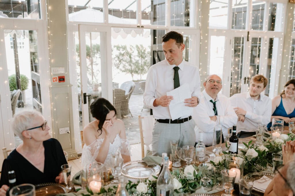 Groom gives wedding speech to guests at reception.
